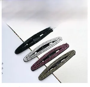 Detailed close-up of four sparkling rhinestone oval hair clips in assorted elegant colors