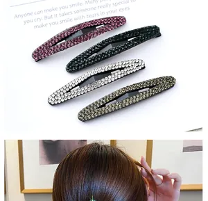 Detail of four oval rhinestone hair clips in purple, green, silver, and champagne colors