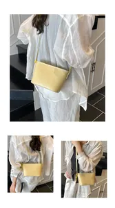Minimalist light yellow woven bucket bag shown worn as a crossbody and shoulder bag
