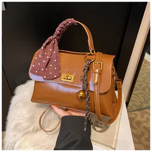 Close-up of vintage brown shoulder bag with scarf-wrapped handle and metal clasp