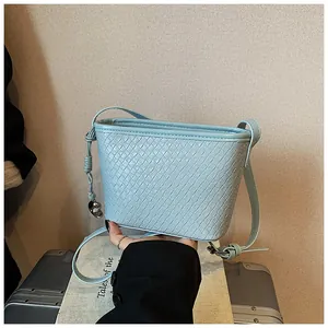 Detail shot of light blue woven bucket bag with elegant leather knot and silver charm