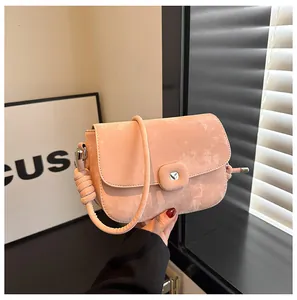 Detailaufnahme der rosa Umhängetasche aus Wildleder mit Herz-Metallschnalle und Knotengurt