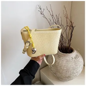 Close-up of beige woven texture shoulder bag with heart pendant in a minimalist setting