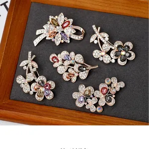 Detailed macro view of five vintage crystal floral and butterfly brooches in gold finish