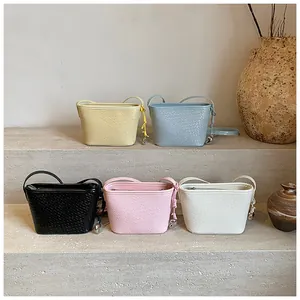 Detailed view of woven texture bucket bags in five pastel colors with metal sphere charms