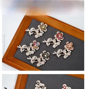 Detailed macro view of crystal flower brooches in five colors on a wooden background
