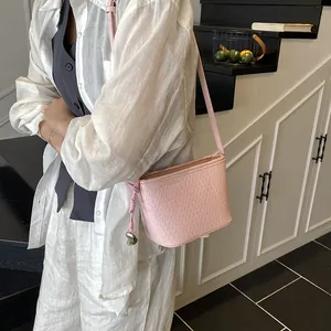 Pink woven bucket bag for women featuring a silver heart charm and leather shoulder strap