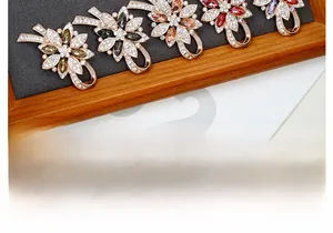 Detail of five floral crystal brooches with rhinestones on a wooden display tray