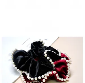 Detail view of burgundy velvet scrunchie with elegant faux pearl trim and soft texture