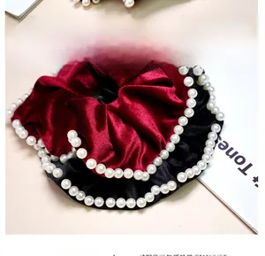 Detail of elegant velvet hair scrunchies with white pearls in wine red and black