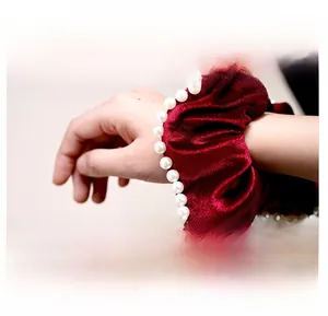 Detail of red velvet scrunchie with faux pearl edges worn as an elegant wrist accessory