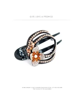 Detail of elegant black hair claw clip featuring a floral design with orange and white rhinestones