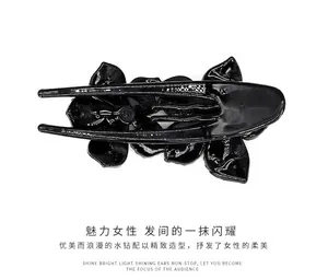 Detail of elegant black floral hair claw with sparkling rhinestones and glossy finish