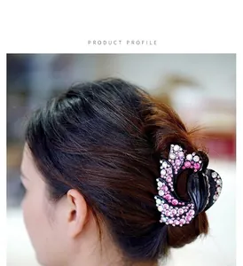 Detail view of a black swan-shaped hair claw clip with pink and white rhinestones