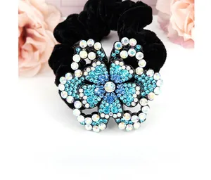 Macro di un fiore di strass blu su un elastico per capelli in velluto nero con fiori