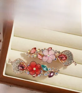 Gros plan de fleurs en maille faites main et strass colorés sur pinces à cheveux or rose