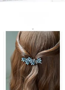 Detailaufnahme der blauen blumenförmigen Haarspange in braunem gewelltem Haar