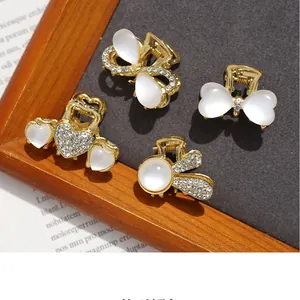 Detaillierte Makroaufnahme goldener Mini-Haarklammern mit Katzenaugenstein und Strass