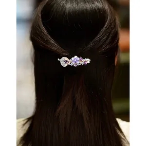 Barrette florale avec strass violets portée sur de longs cheveux châtains foncés