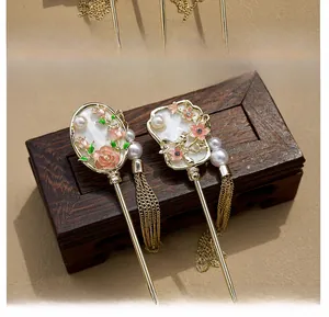 Detail of elegant gold hairpin set with pink enamel petals, pearls and long tassels