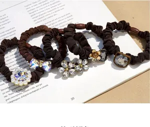Detail of four brown elastic hair scrunchies with pearls and sparkling crystal flowers