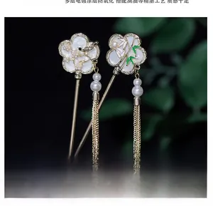Detailed close-up of golden hairpins with resin flowers, pearls and tassel chains