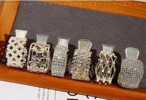 Set of six gold metal hair claws featuring rhinestones and pearls on a grey display