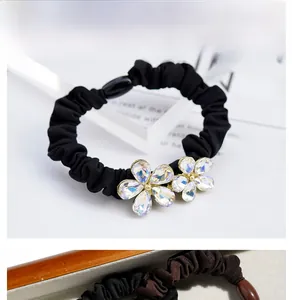 Detailed view of the iridescent crystal flower ornaments on a black pleated scrunchie