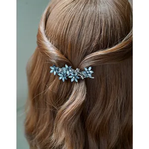 Eleganter dunkelblauer Blumen-Haarclip mit Kristallen auf braunem, gewelltem Haar