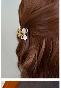 Nahaufnahme einer goldenen Schmetterlings-Haarklammer mit Opalsteinen und Kristallen im Haar