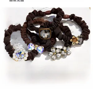 Close-up of elegant coffee-toned hair ties with pearls, crystals, and metal flowers