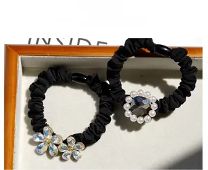 Detail of high-elastic black hair ties with crystal flowers and pearl embellishments