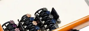 Detailed macro view of black acrylic hair claws with elegant inlaid rhinestone flowers