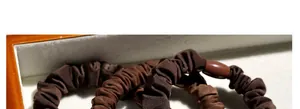 Macro shot of dark brown pleated fabric hair tie with smooth round decorative beads