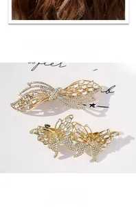 Detailed view of luxury gold butterfly hair clips with white rhinestones on white backdrop