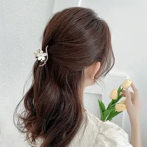 Elegante pinza per capelli a fiore dorata con perle e strass su capelli di donna