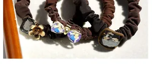 Detail of coffee brown elastic hair tie with crystal gemstones and floral charms