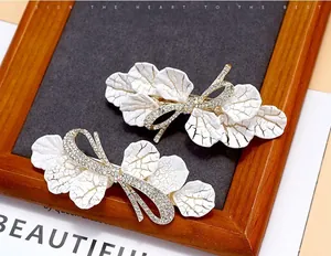 Detailed macro of white petal hair clips with sparkling rhinestone bow accents