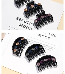Close-up of black acrylic hair claw clip with colorful rhinestone flower design
