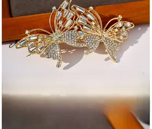 Detail of elegant gold alloy butterfly hair clip featuring white sparkling rhinestones