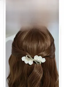 Detail of elegant white enamel leaf hair clip with rhinestones worn by a model