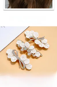 Detailed close-up of elegant leaf hair clips with white resin, pearls and crystals