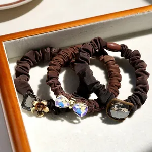 Three-piece set of brown elastic hair scrunchies with crystal and floral alloy accents