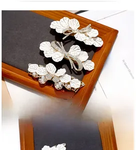 Close-up of elegant white leaf hair clips with rhinestones and gold metal spring clamps