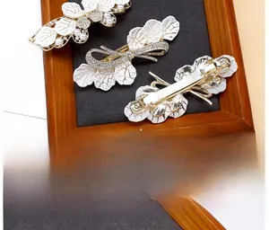 Macro detail of alloy spring clips with white leaves, faux pearls and crystals