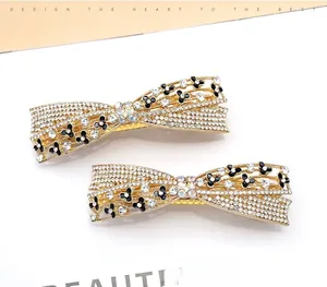 Detail of gold-plated alloy bow hair clips with rhinestones and black clover motifs