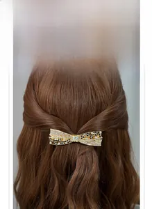 Detail of a large rhinestone bow spring clip with black floral accents on wavy hair