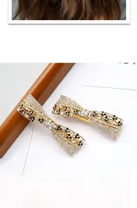 Detail of rhinestone bow hair clips with gold alloy and black flower accents