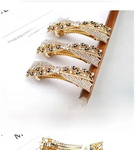 Detailed view of rhinestone bow hair clips with black enamel flowers on gold alloy base