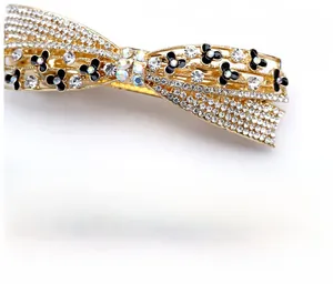Macro detail of bow-shaped rose gold hair clip featuring sparkling rhinestones and floral inlay